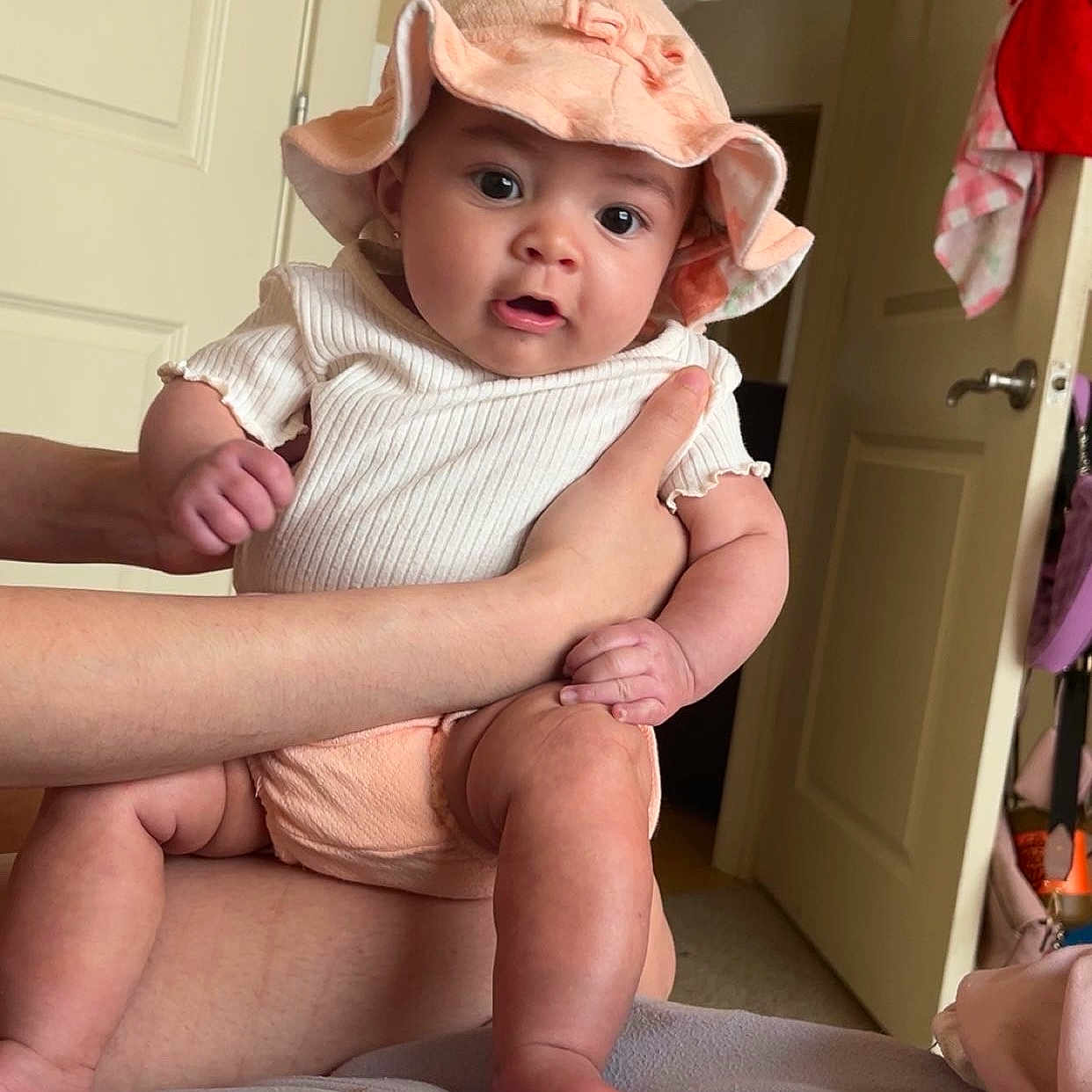 Eilani is registered to the contest to win money with this photo: apparel, baby, bed, blanket, child, clothing, cute, door, expression, face, foot, hands, hat, human, indoor, infant, leg, person, room, skin