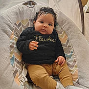 Elliyana joined the competition — help win amazing prizes! baby, child, infant, portrait, sitting, bouncer, baby_chair, smiling, wide_eyed, curly_hair, black_sweater, text_on_clothing, mustard_pants, socks, blanket, cushion, indoor, cozy, patterned_background, flawless