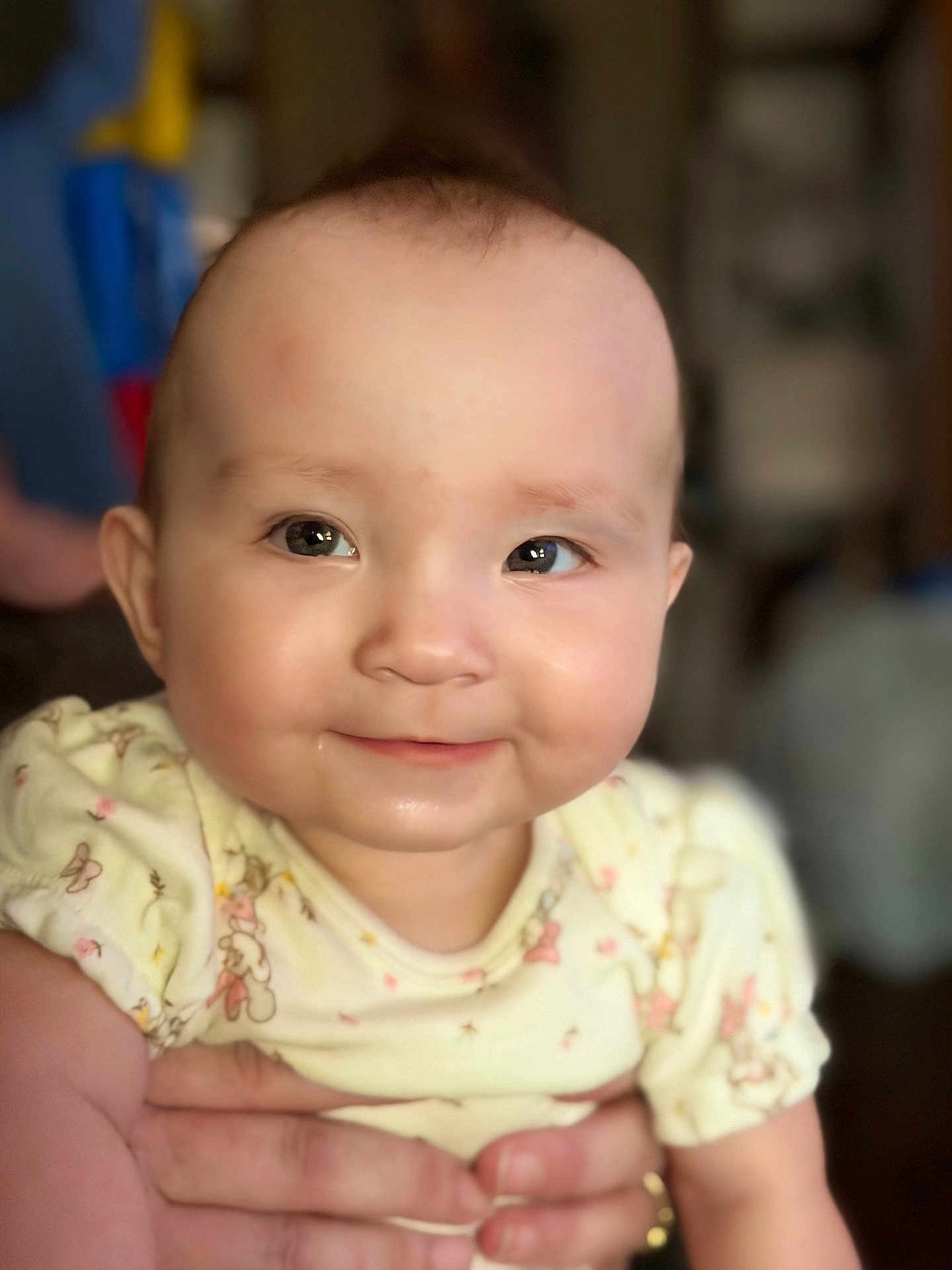 River is registered to the contest to win money with this photo: baby, infant, smile, face, hands, yellow_clothing, cute, portrait, child, person, indoor, soft_light, holding, young_child, skin, expression, happy, closeup, blurred_background, toddler