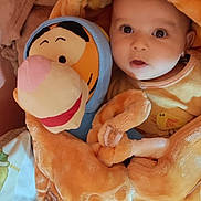 Ryan Hegazi a rejoint le concours — aidez-le/la à gagner de superbes lots ! baby, plush_toy, tigger, orange_outfit, bear_ears, blanket, soft_texture, child, cute, wide_eyes, cozy, bed, stuffed_animal, smiling, infant, clothing, indoors, warm_colors, person, portrait