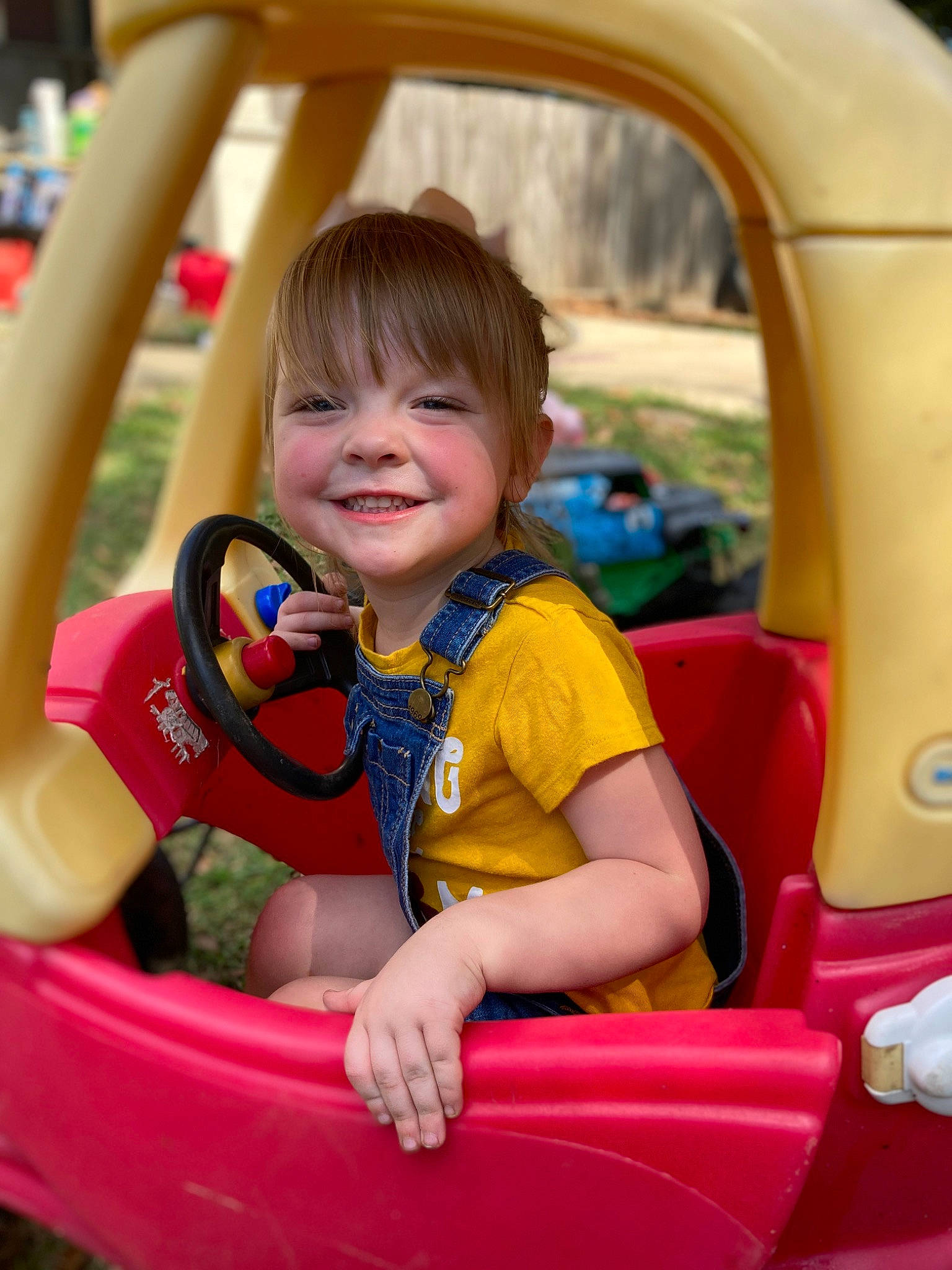 Amelia is registered to the contest to win money with this photo: auto_part, automotive_design, automotive_exterior, car_seat, child, fun, grass, happy, joy, leisure, motor_vehicle, person, public_space, recreation, riding_toy, skin, smile, steering_wheel, tire, toddler