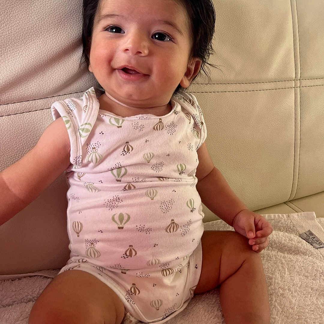 Ezékias a rejoint le concours — aidez-le/la à gagner de superbes lots ! baby, child, clothing, comfortable, couch, cute, expression, face, furniture, hair, happy, indoors, infant, onesie, portrait, relaxed, sitting, skin, smiling, young