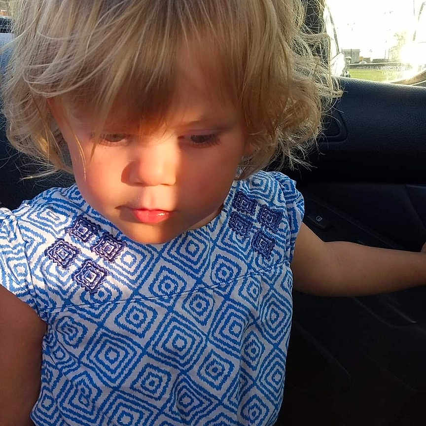 Amelia is registered to the contest to win money with this photo: accessories, belt, blonde, car, child, clothing, cushion, dress, face, female, girl, hair, happy, head, homedecor, person, photography, portrait, transportation, vehicle