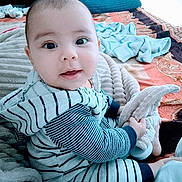 Eliam joined the competition — help win amazing prizes! baby, child, striped_clothing, plush_toy, bed, blanket, soft_toy, happy, smiling, indoors, cute, cozy, person, infant, sitting, face, expression, warm, comfort, young