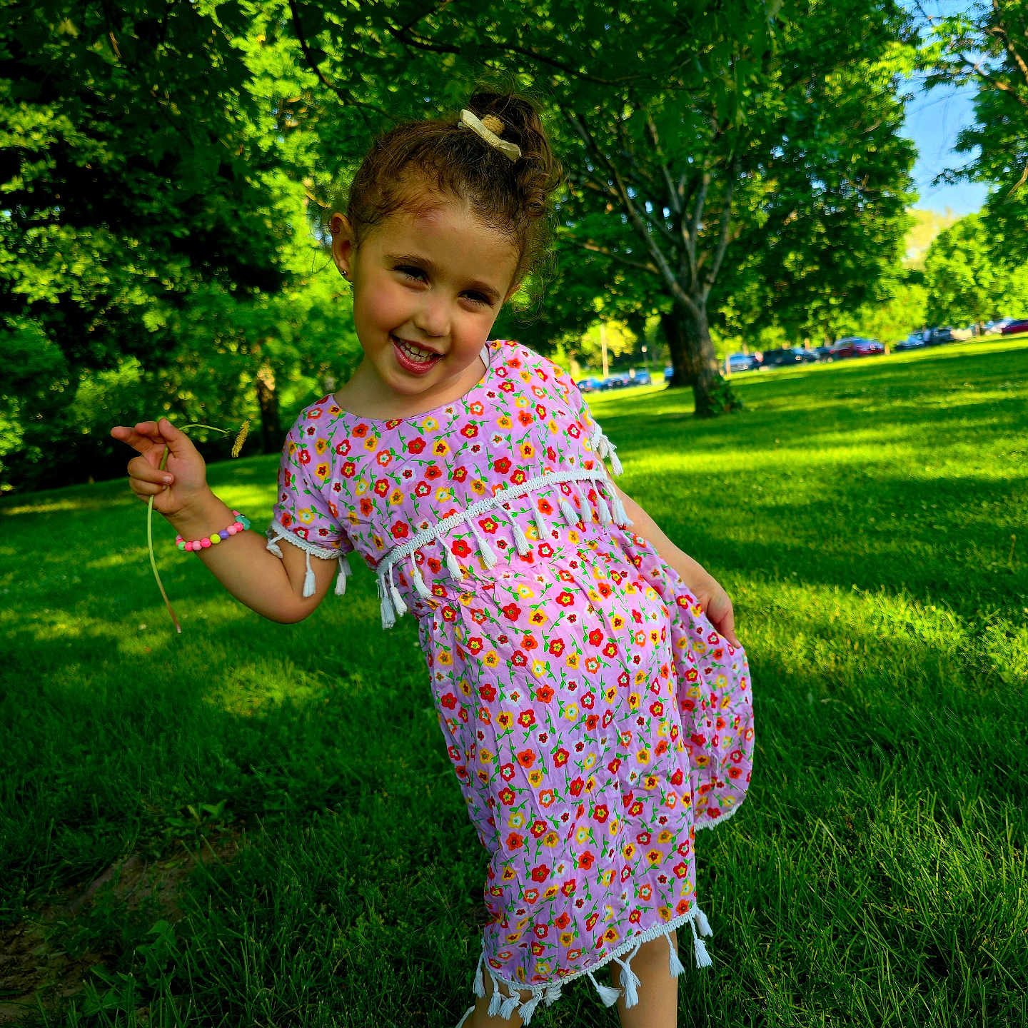 Maria joined the competition — help win amazing prizes! child, girl, toddler, smiling, portrait, outdoor, park, garden, grass, trees, sunlight, summer, dress, floral_pattern, hair_bow, bracelet, shoes, standing, leaning, flower