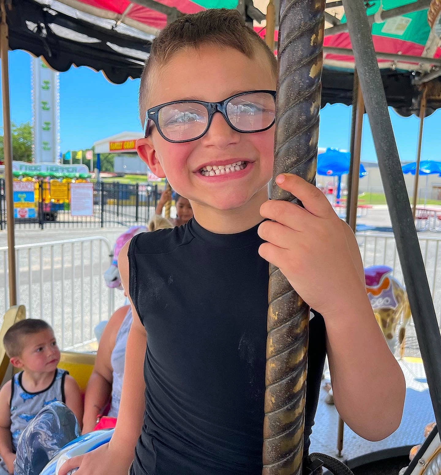 Orion is registered to the contest to win money with this photo: child, city, event, eyewear, fun, glasses, happy, joy, leisure, nonbuilding_structure, person, personal_protective_equipment, recreation, sky, smile, t_shirt, thumb, toddler, tourism, travel