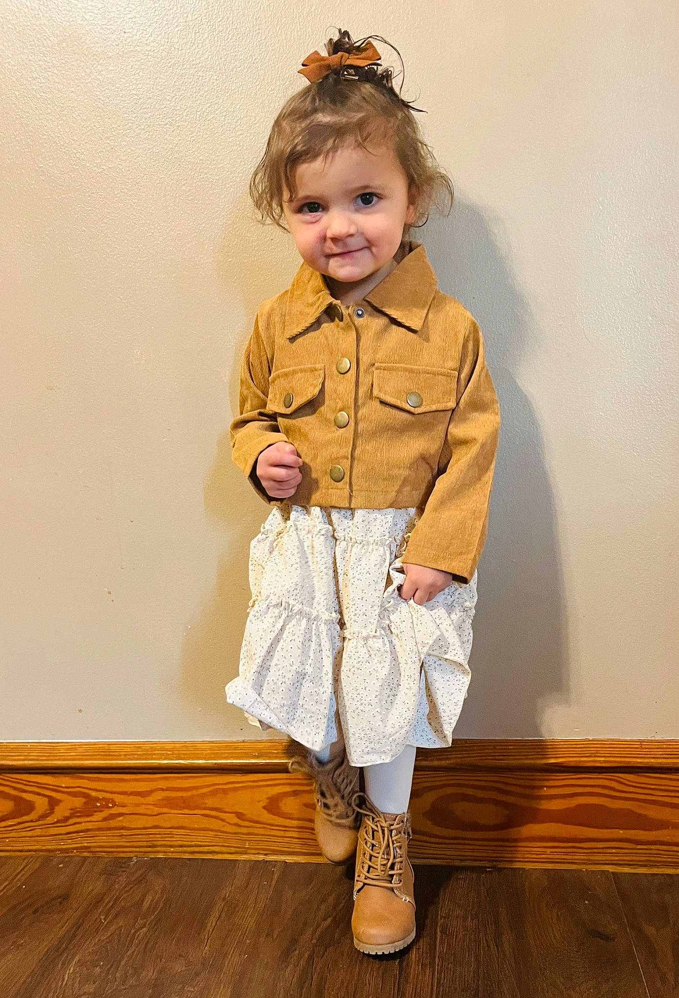 Sophia is registered to the contest to win money with this photo: arm, baby_toddler_clothing, blond, face, facial_expression, fashion_design, flooring, hair, happy, hardwood, human_body, joy, knee, leg, person, skin, sleeve, smile, toddler, vintage_clothing