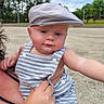 baby, child, hat, cap, overalls, striped_clothing, outdoor, sky, cloudy, greenery, person, infant, cute, hand, face, portrait, summer, nature, holding, curious