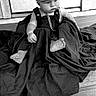 baby, child, cap, chain, black_and_white, portrait, sitting, floor, wood, cloth, outfit, foot, hand, expression, cute, indoor, hat, infant, young_child, fashion