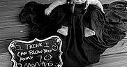 Lucas is registered to the contest to win money with this photo: baby, child, black_and_white, chalkboard, sign, cap, overalls, floor, wooden_floor, fabric, cloth, sitting, milestone, portrait, cute, infant, person, indoors, decor, humor