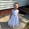 casual, child, concrete, curly_hair, curly_hair_buns, daylight, dress, expression, girl, house, outdoor, person, portrait, shadow, sidewalk, siding, standing, steps, sunlight, white_dress