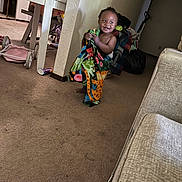 Dnero joined the competition — help win amazing prizes! toddler, child, blanket, smiling, indoor, carpet, table, household_items, toy_stroller, clothing, person, wall, furniture, living_room, colorful, happy, standing, home, cozy, playful