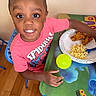 Kingston is registered to the contest to win money with this photo: child, boy, smiling, spiderman_shirt, food, fried_chicken, macaroni_and_cheese, plate, table, yellow_ball, chair, wooden_floor, indoor, happy, kid_table, colorful, meal, person, portrait, dining