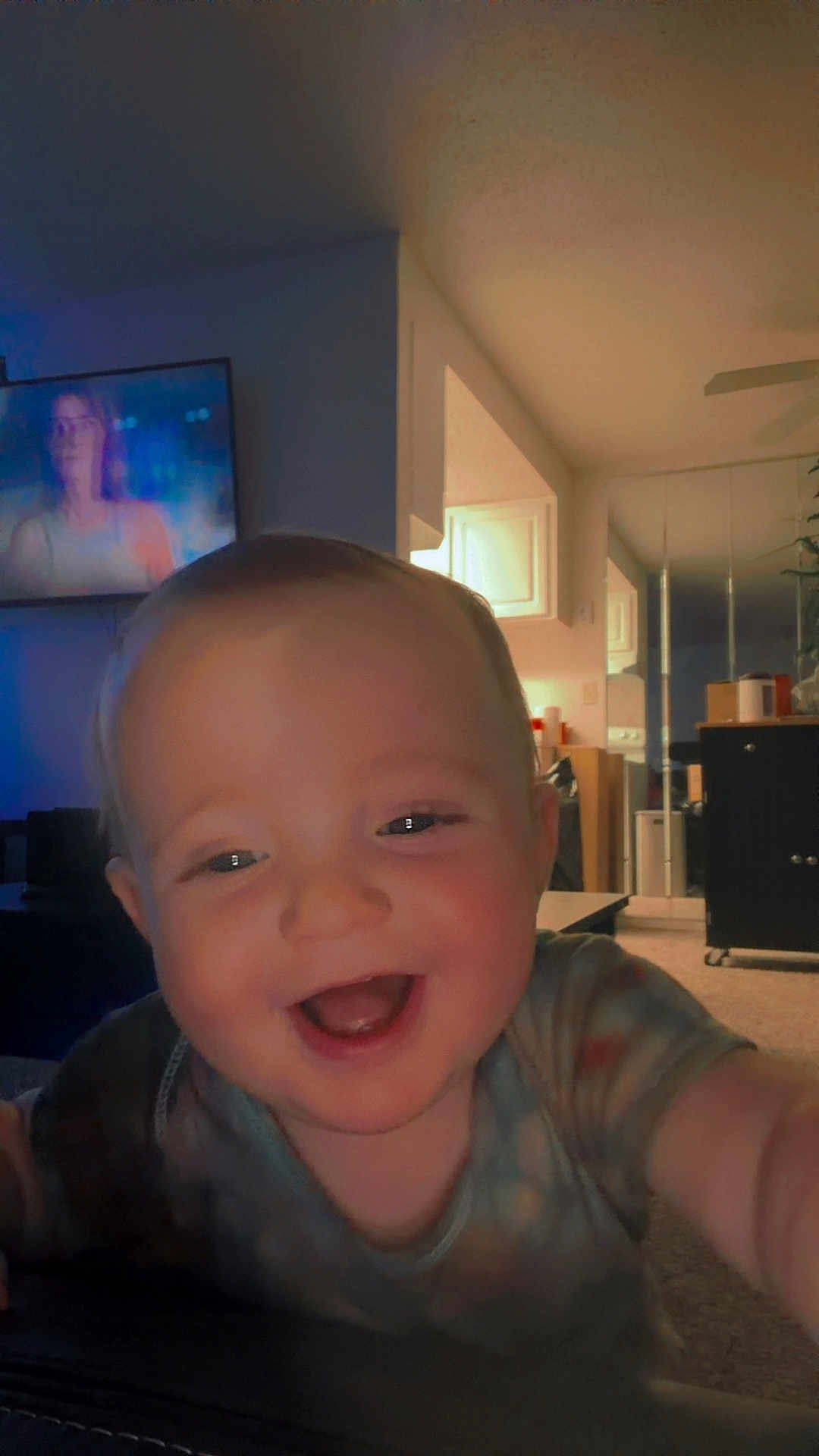 Caleb joined the competition — help win amazing prizes! baby, infant, smiling, close_up, face, happy, laughing, onesie, indoor, living_room, television, couch, carpet, cabinet, mirror, cheerful, portrait, arm, hand, ceiling_fan