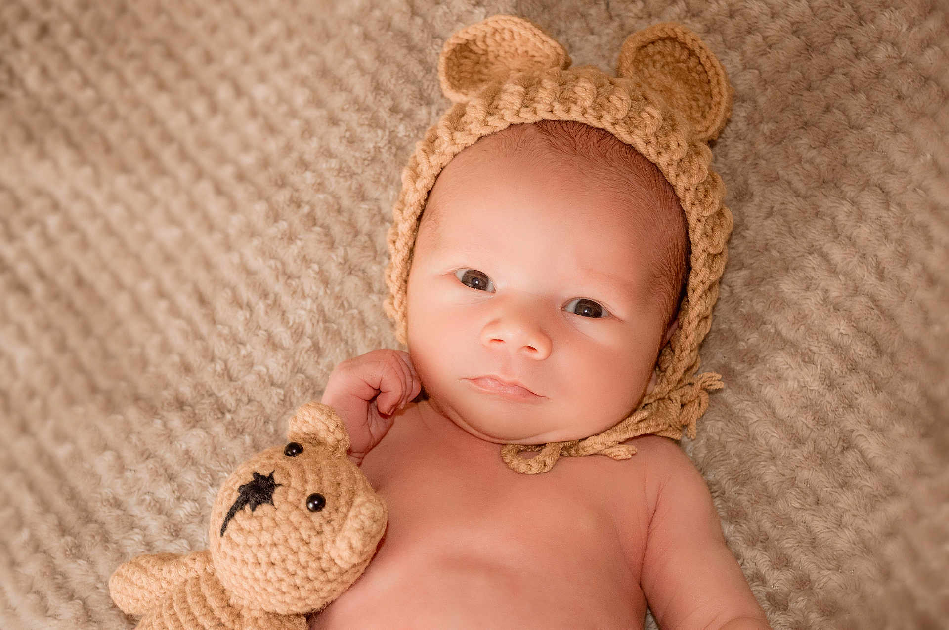 Jacek is registered to the contest to win money with this photo: baby, infant, knitted_hat, bear_ears, crocheted_toy, teddy_bear, blanket, soft_texture, cute, portrait, child, newborn, relaxed, indoors, closeup, skin, lying_down, hand, expression, warm_colors