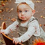 toddler, child, baby, headband, bow, wooden_chair, outdoor, autumn, leaves, pathway, floral_clothing, curious, portrait, holding, nature, cute, young_child, fall, person, innocence