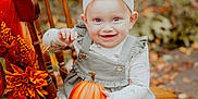 Scarlett is registered to the contest to win money with this photo: baby, child, pumpkin, chair, autumn, fall, outdoor, smiling, headband, white_bow, dress, tights, shoes, wooden_chair, decorations, orange, leaves, seasonal, cute, portrait