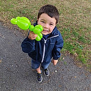 Chemsey a rejoint le concours — aidez-le/la à gagner de superbes lots ! child, boy, balloon, green_balloon, outdoor, park, grass, smiling, happy, jacket, sneakers, shorts, stroller, ground, gravel, playful, toy, casual, daylight, portrait