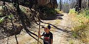 Chemsey a rejoint le concours — aidez-le/la à gagner de superbes lots ! child, boy, walking_stick, forest, path, trees, rock, shadow, sunlight, nature, outdoor, cap, shorts, tshirt, smile, adventure, hiking, daytime, plants, shoes