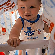 Asher joined the competition — help win amazing prizes! baby, baby_clothes, blanket, child, clothing, crib, curly_hair, cute, face, foot, hand, home, indoor, infant, person, playful, smiling, soft_toys, toddler, toy