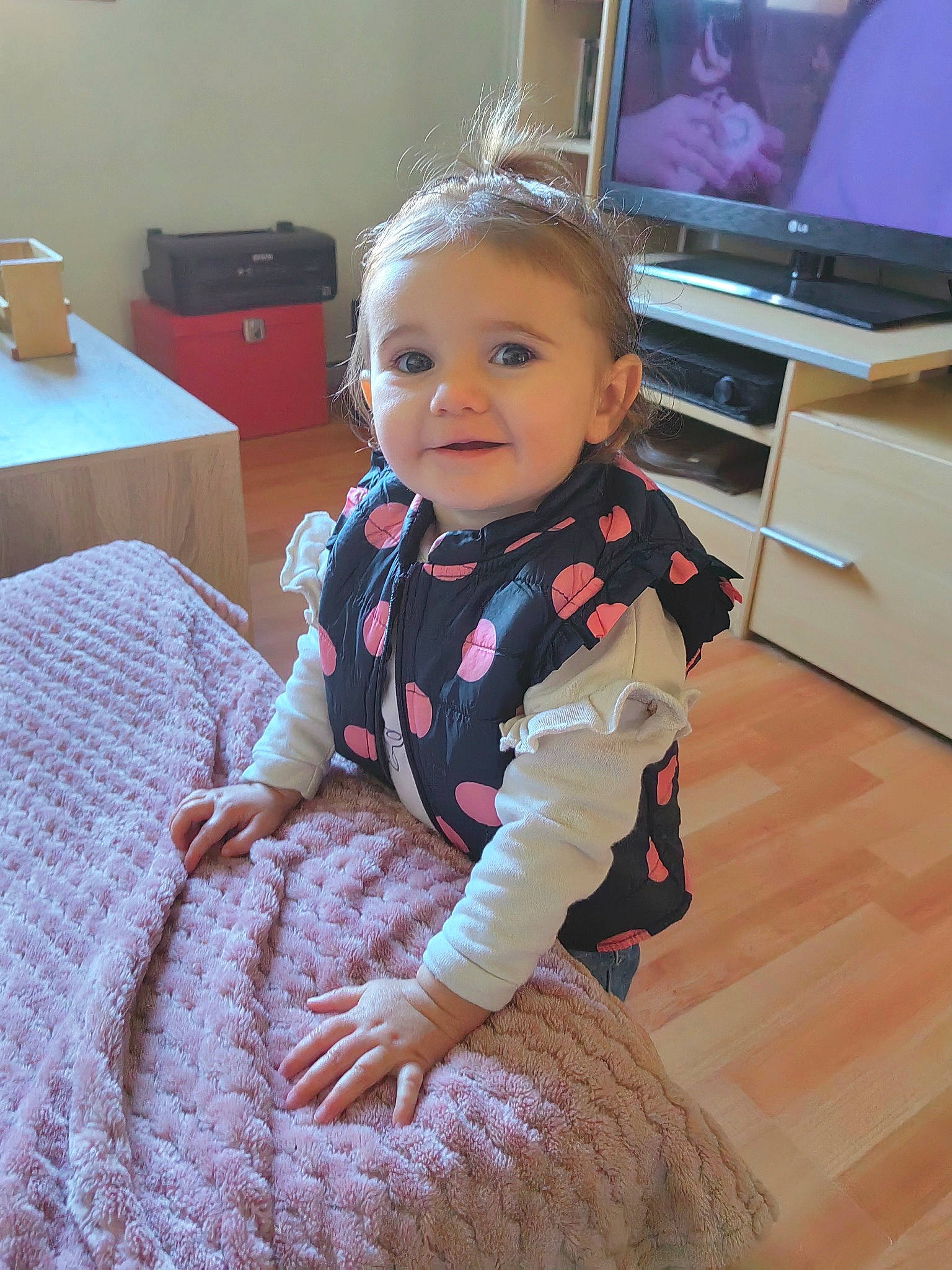 Wendy participe au concours pour gagner de l'argent avec cette photo : baby, baby_toddler_clothing, child, comfort, entertainment_center, floor, flooring, home_appliance, iris, joy, pattern, person, pink, room, sitting, skin, sleeve, smile, television, television_set
