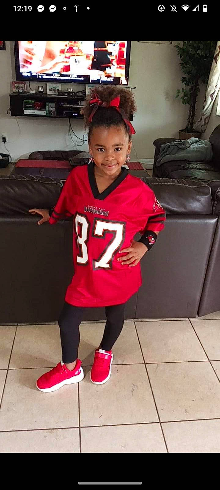 Sariah joined the competition — help win amazing prizes! baby_toddler_clothing, boot, couch, floor, flooring, footwear, jersey, joy, leg, person, red, shoe, sleeve, smile, sneakers, sock, sports_uniform, sportswear, sweatpant, t_shirt