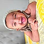 baby, smiling, knitted_hat, quilt, yellow, bedroom, happy, child, infant, cute, face, skin, arm, hand, lying_down, soft_focus, button, textile, headwear, indoors