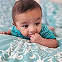 Alzaan is registered to the contest to win money with this photo: baby, infant, child, face, hand, fingers, blanket, pattern, striped_clothing, blue, teal, white, bed, lying_down, cute, portrait, indoors, young, closeup, curious