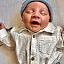baby, infant, child, hat, blue_hat, white_shirt, denim_jeans, clothing, sleeping, smiling, cute, soft_blanket, portrait, indoor, newborn, relaxed, peaceful, small_person, casual_wear, adorable