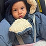 baby, child, car_seat, jacket, hood, blanket, fur_trim, face, eyes, clothing, warm, indoor, seatbelt, infant, portrait, cute, winter_wear, soft_texture, close_up, sitting