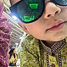 blurry_background, candid, child, closeup, curious, face, fashion, head, indoor, lips, nose, pattern, people, person, portrait, reflection, serious_expression, sunglasses, traditional_clothing, young