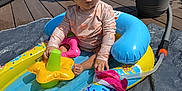 Kylani joined the competition — help win amazing prizes! casual_clothing, child, curly_hair, daylight, deck, expression, flower_toy, garden, hose, inflatable_pool, outdoor, person, playtime, potted_plants, residential_area, summer, sunny, toddler, toy, water