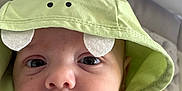 Lyo participe au concours pour gagner de l'argent avec cette photo : baby, hoodie, green_clothing, cute, infant, face, eyes, hand, soft_surface, closeup, child, portrait, casual_wear, expression, hood, fabric, skin, young, indoors, person