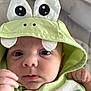 baby, hoodie, green_clothing, cute, infant, face, eyes, hand, soft_surface, closeup, child, portrait, casual_wear, expression, hood, fabric, skin, young, indoors, person