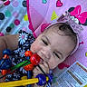 baby, child, headband, pink, toy, wooden_toy, beads, colorful, playmat, minnie_mouse, heart, flower_pattern, clothing, infant, closeup, face, hand, cute, indoors, portrait
