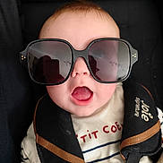 Gabriel a rejoint le concours — aidez-le/la à gagner de superbes lots ! baby, child, sunglasses, car_seat, seat_belt, open_mouth, striped_shirt, face, head, infant, cute, black, clothing, safety, expression, person, portrait, young, accessory, close_up