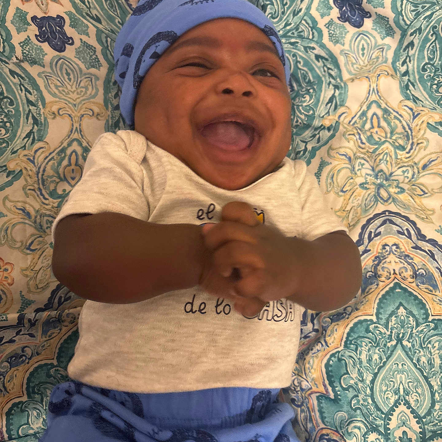 Khazir joined the competition — help win amazing prizes! baby, blue_hat, blue_pants, child, close_up, clothing, cute, fabric, hands_clasped, happy, human, indoors, infant, joyful, laughing, lying_down, patterned_blanket, portrait, smiling, text_on_clothing