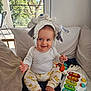 baby, child, smiling, hat, stuffed_animal, toy, musical_keyboard, cushion, sofa, indoor, window, sunlight, clothing, pants, foot, hand, happy, infant, playful, home
