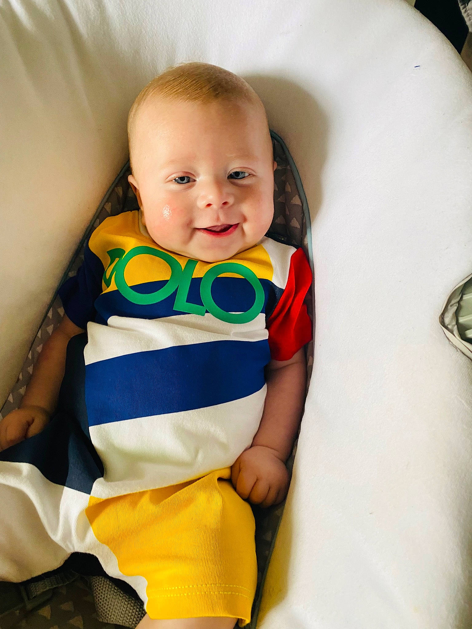 Elliot is registered to the contest to win money with this photo: arm, baby, baby_products, baby_toddler_clothing, cheek, child, comfort, face, hair, happy, human_body, iris, neck, pattern, person, skin, sleeve, smile, standing, t_shirt
