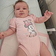 Jaclyn is registered to the contest to win money with this photo: baby, infant, crib, onesie, pink_clothing, minnie_mouse, cartoon_character, bedding, blanket, soft_furnishing, child, head, face, skin, arms, legs, cute, indoors, person, sleeping_area