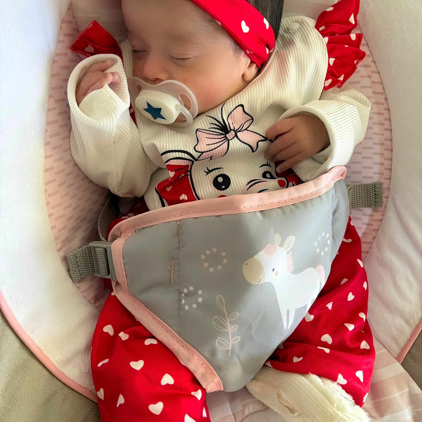 Inaya a rejoint le concours — aidez-le/la à gagner de superbes lots ! baby, baby_seat, child, closeup, clothing, comfort, cozy, cute, footwear, heart_pattern, indoors, infant, pacifier, peaceful, portrait, red_headband, rest, sleeping, soft_fabric, unicorn_print