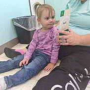 Xiomara Marie Poland is registered to the contest to win money with this photo: toddler, child, adult, indoor, floor, flashcard, learning, curious, casual_clothing, jeans, sneakers, long_sleeve_shirt, hair_tied, trash_can, light_blue_wall, smiling, person, education, reading, interaction