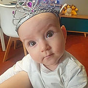 Mila a rejoint le concours — aidez-le/la à gagner de superbes lots ! baby, tiara, crown, indoor, child, face, curious, white_clothing, furniture, chair, stuffed_animals, toy, living_room, person, cute, infant, headwear, closeup, portrait, home