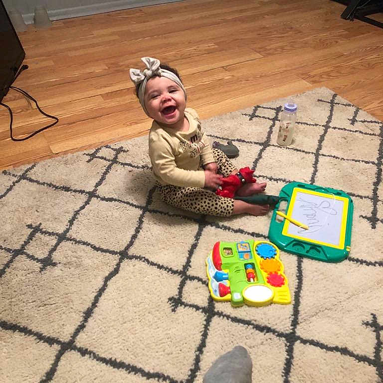 Amoni is registered to the contest to win money with this photo: architecture, baby, building, clothing, face, footwear, furniture, happy, head, homedecor, indoors, livingroom, pants, person, photography, portrait, shoe, sitting, table, toy