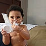 Amoni is registered to the contest to win money with this photo: toddler, child, baby, cream, face_cream, bed, diaper, curly_hair, indoor, skin, hand, headboard, pillow, container, messy, cute, sitting, expression, room, furniture