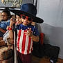 child, kids, hat, sunglasses, baseball_bat, sofa, indoor, wall_art, wood_floor, casual, glasses, blue_shirt, red_and_white_stripes, furniture, person, relaxing, portrait, group, home, decor