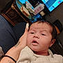 Alexis is registered to the contest to win money with this photo: baby, infant, person, hand, tattoo, lotion, plate, sandwich, television, furniture, blanket, heart_doodle, living_room, clothing, face, skin, expression, indoors, holding, curly_hair