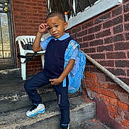 Trevon Jr is registered to the contest to win money with this photo: child, boy, stairs, backpack, blue_clothing, sneakers, brick_wall, concrete, outdoor, pose, smile, window, door, hand_gesture, casual, young, person, urban, fashion, street