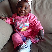 So'Lana joined the competition — help win amazing prizes! baby, child, smiling, pink_clothing, headband, bow, pacifier, couch, indoor, happy, sitting, footwear, sneakers, person, infant, cute, portrait, cozy, home, comfortable