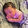 baby, sleeping, blanket, pink_clothing, curly_hair, soft_texture, cozy, infant, peaceful, resting, indoor, cute, newborn, face, hands, toddler, lying_down, child, warm, comfort